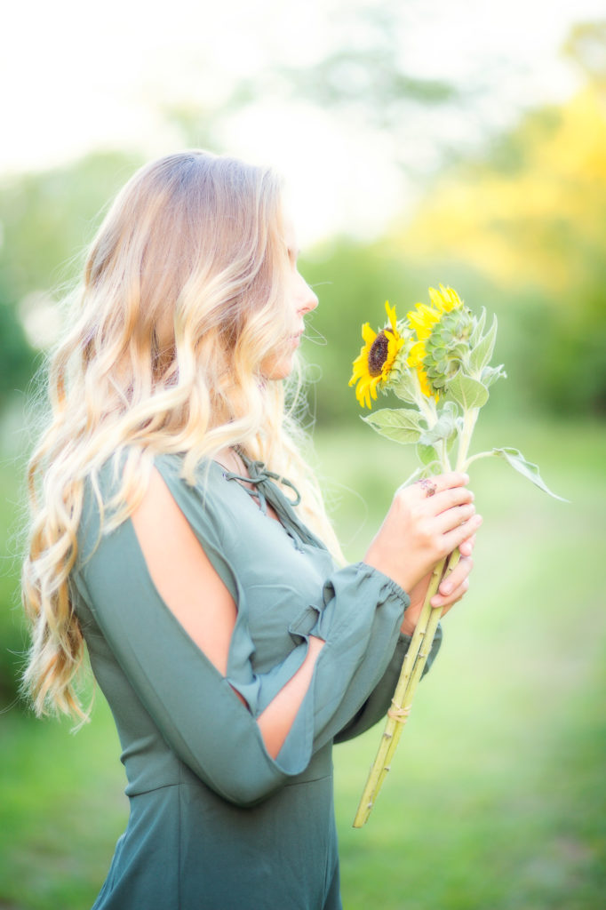 Girl holding sunflowers with a profile view she's not looking at the camera.