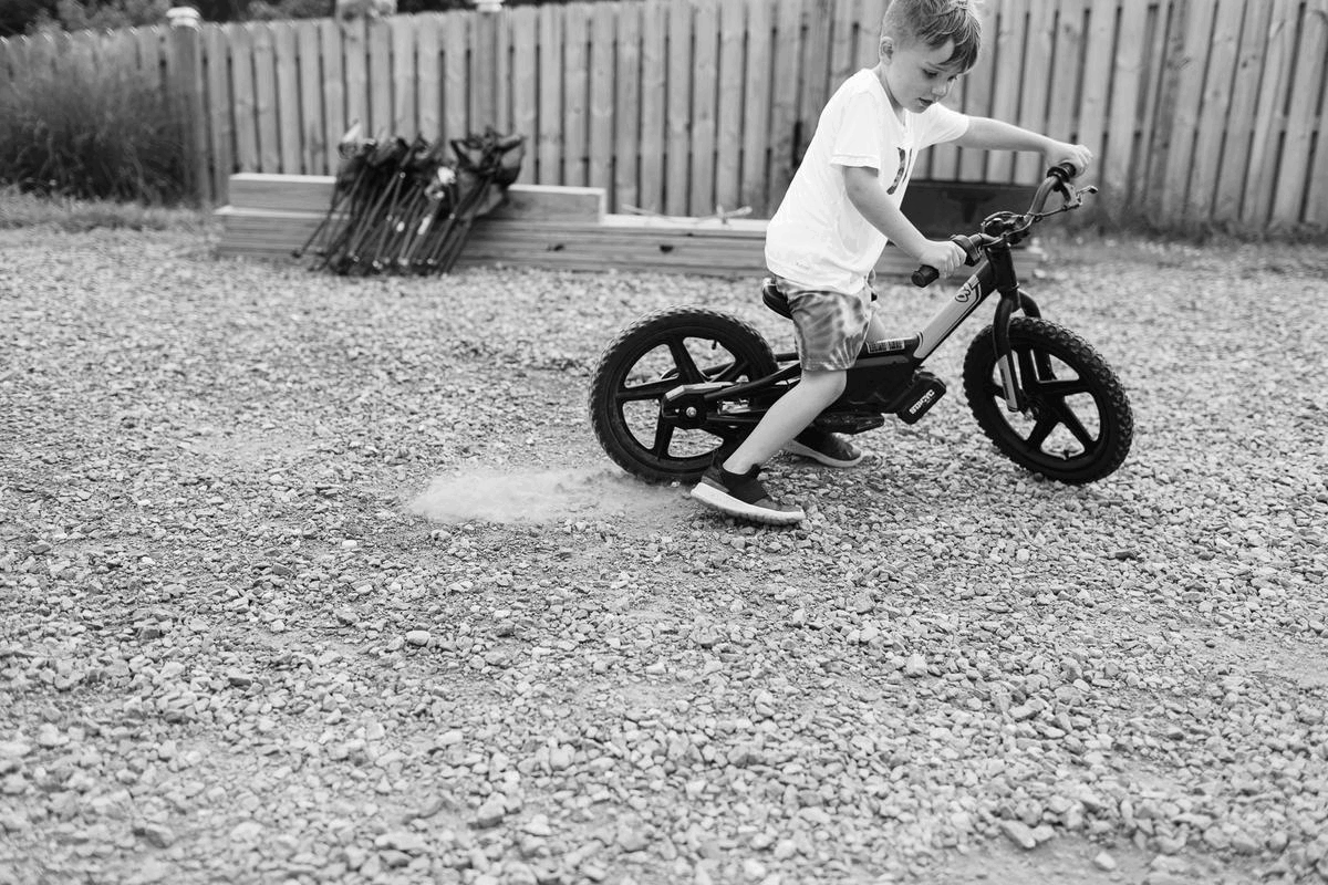 Moving images of a four year old boy riding his dirt bike on gravel.