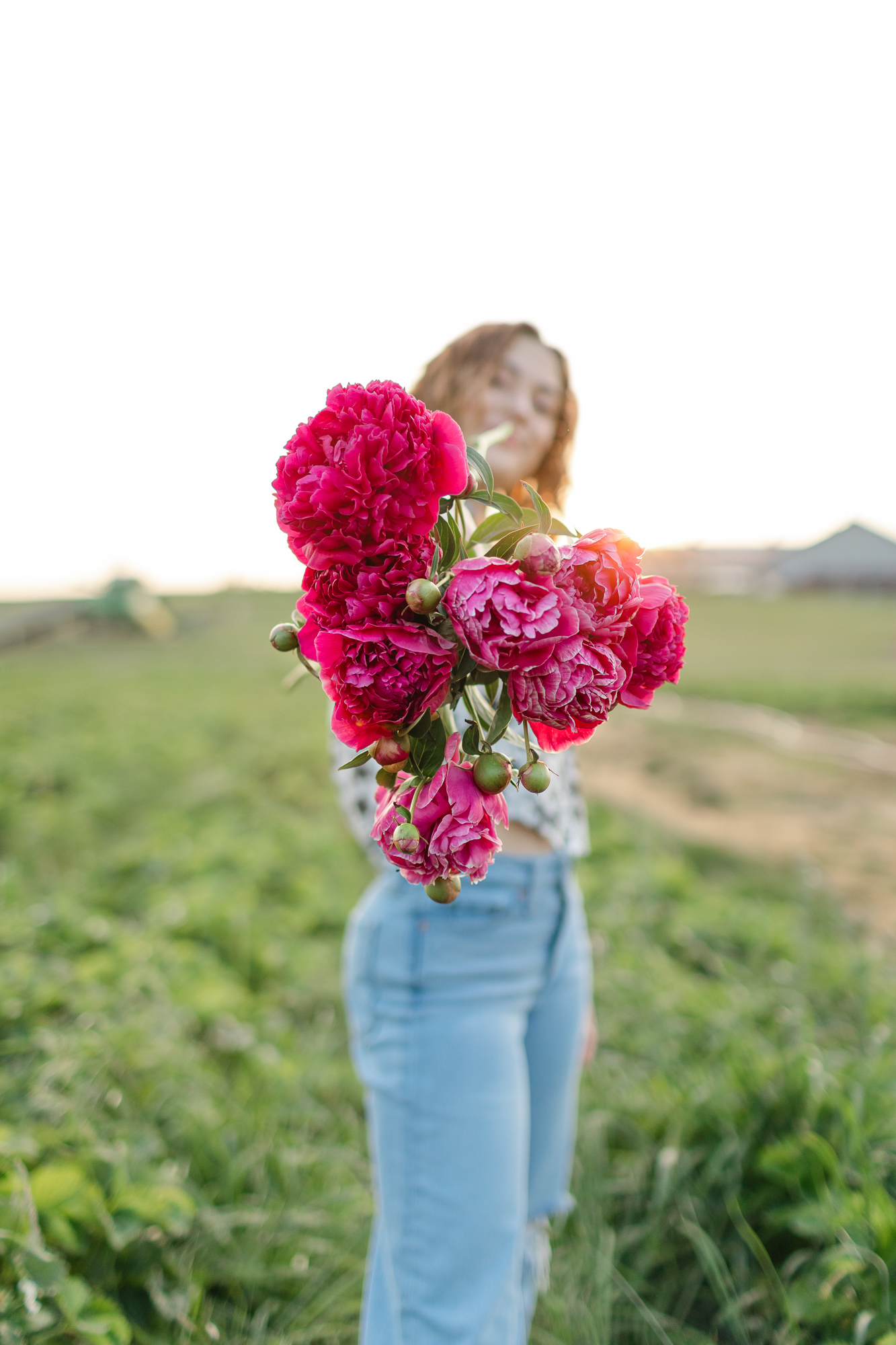 Female holding flowers in a field wearing jeans.