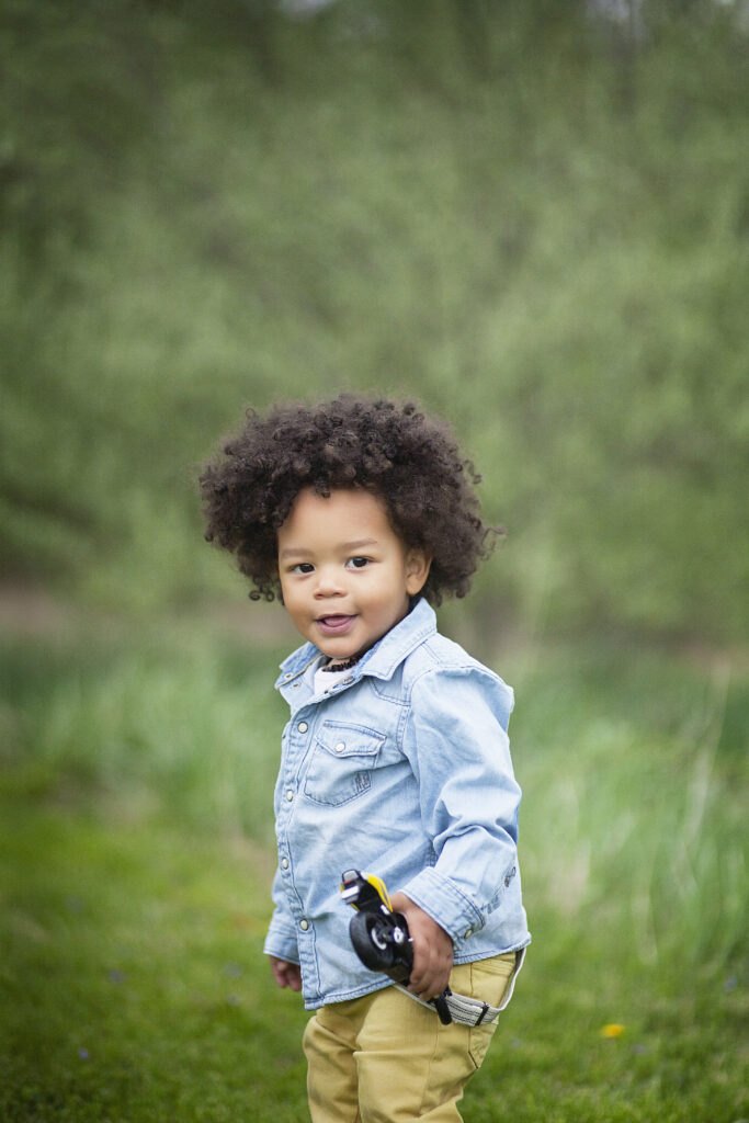 Two year old little boy holding a toy motorcycle with a afro.