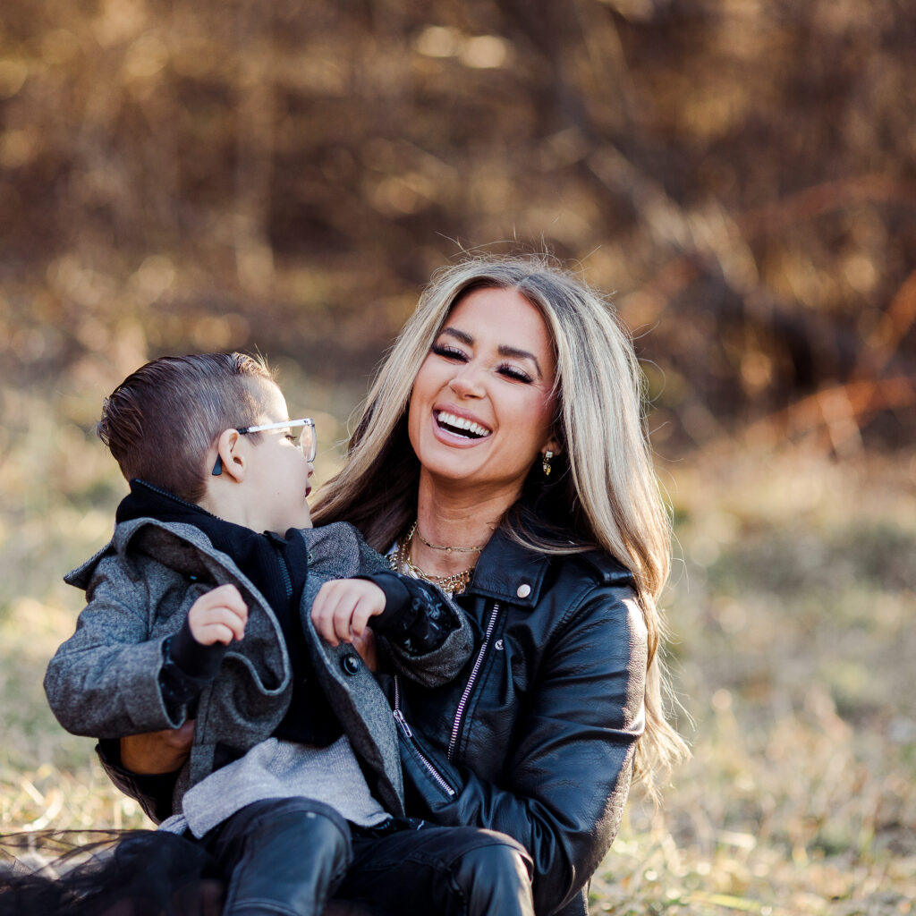 Mother and her six year old son sitting in a field laughing.