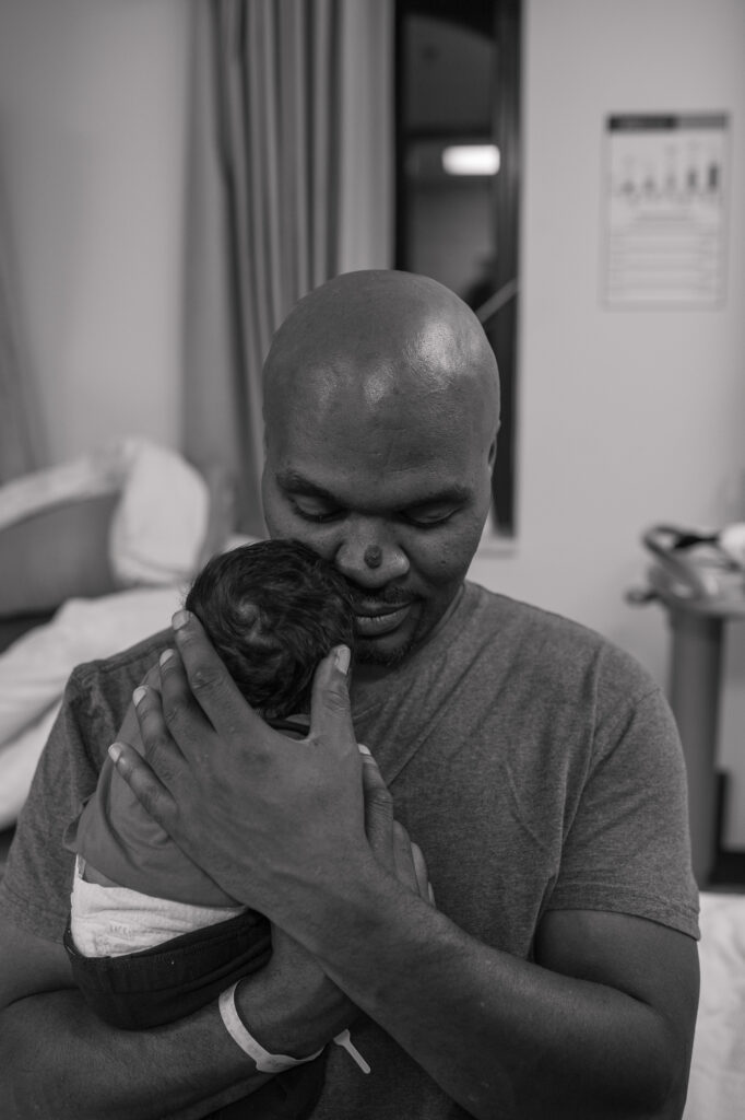 Black & White image of a new dad holding his son.