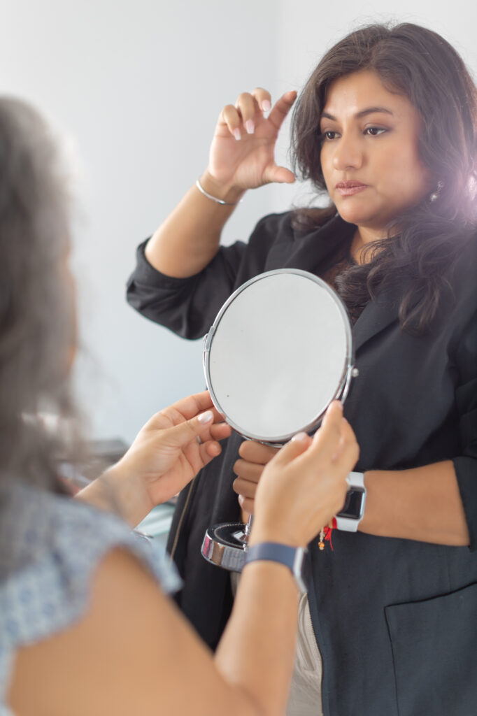 A woman looking at a mirror.
