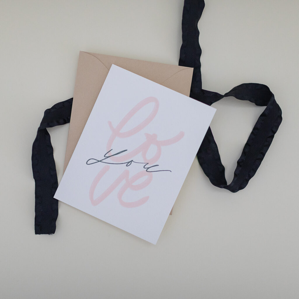 Card that says love you on a black ribbon.