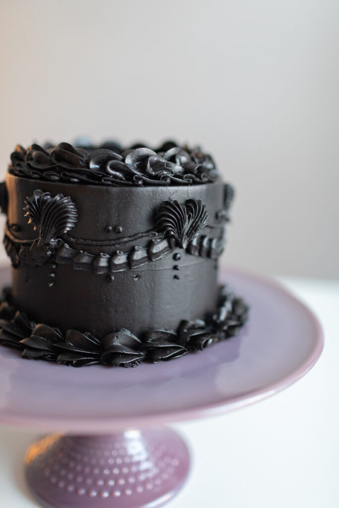 Black cake on a purple plate.